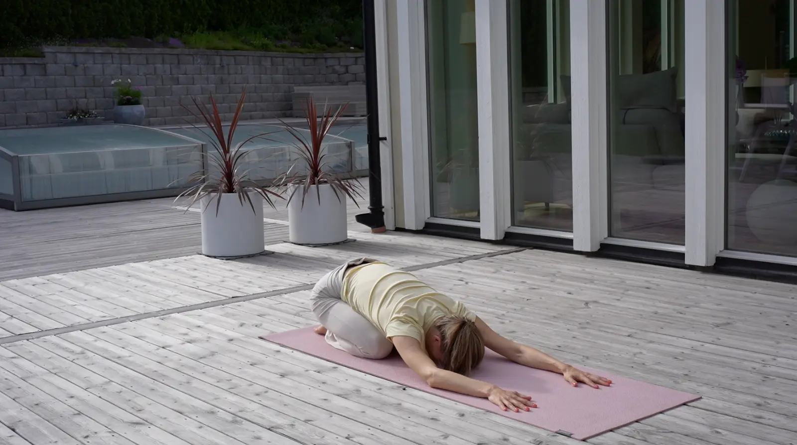 Erika resting in child's pose on a yoga mat on the deck